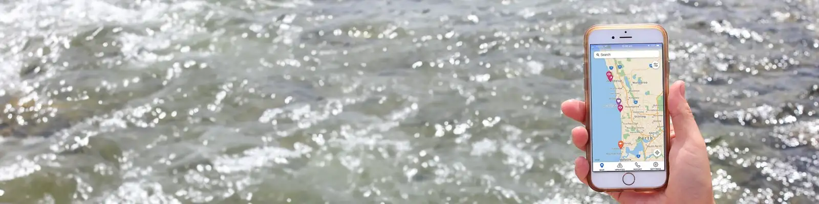 Hand holding a smartphone displaying a map app, with a flowing river in the background.