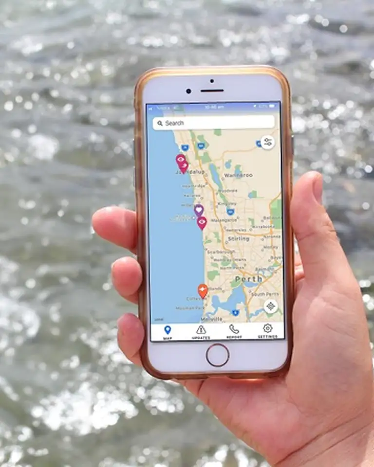Hand holding a smartphone displaying a map app, with a flowing river in the background.