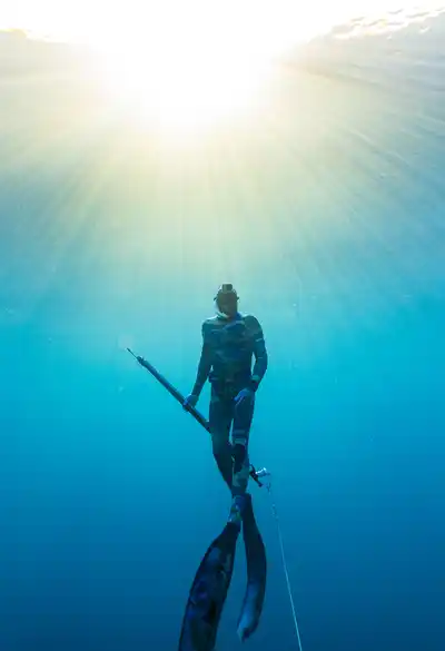 Spearfisher surfacing into sunlight