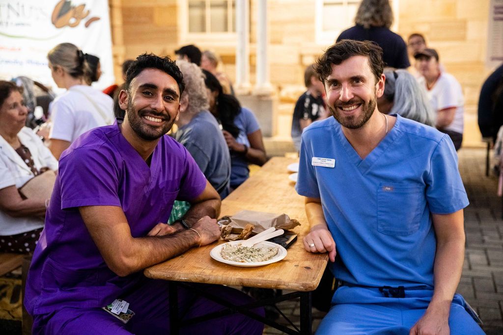 Two healthcare workers in scrubs enjoy a meal at the Randwick Creative Night market
