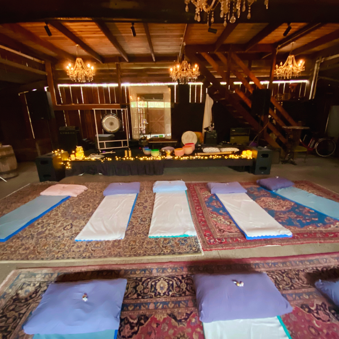 A sound bath set up in a converted barn with instruments and yoga mats laid out.