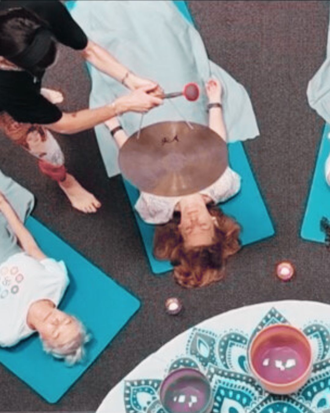 Natalie playing a gong over a sound bath participant.