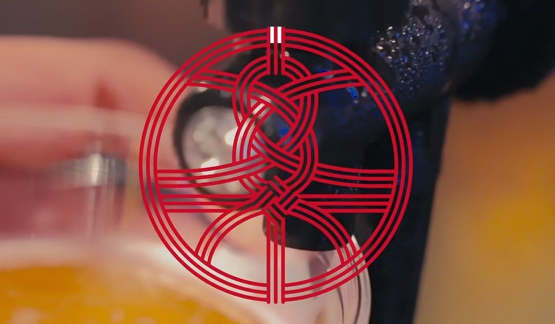 A red circular celtic knot design overlays a blurred background of a hand pouring a drink into a glass.