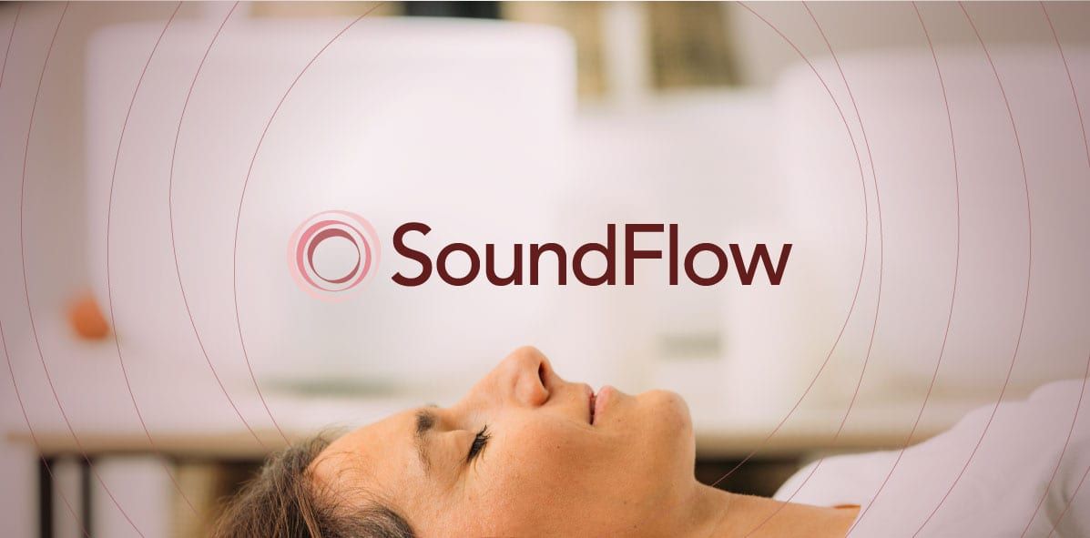 A woman resting peacefully with crystal singing bowls arranged behind her.