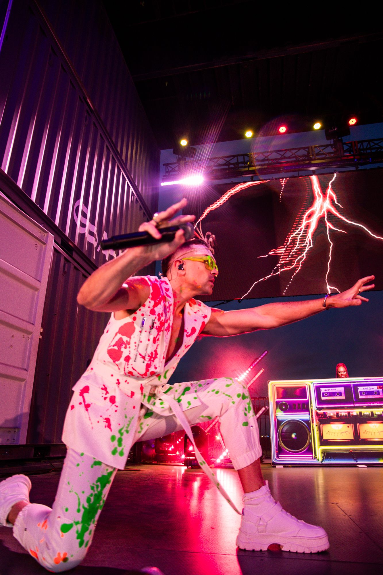 man performing on stage in front of neon signs.
