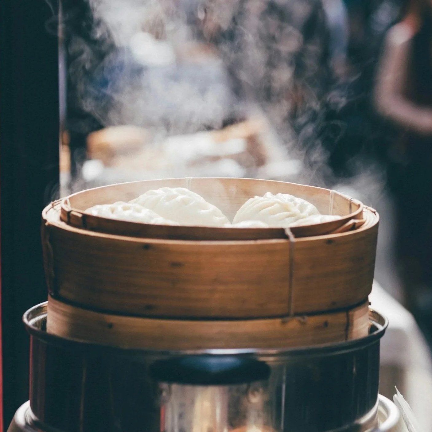 Steaming bamboo basket filled with dumplings, with steam rising into the air.