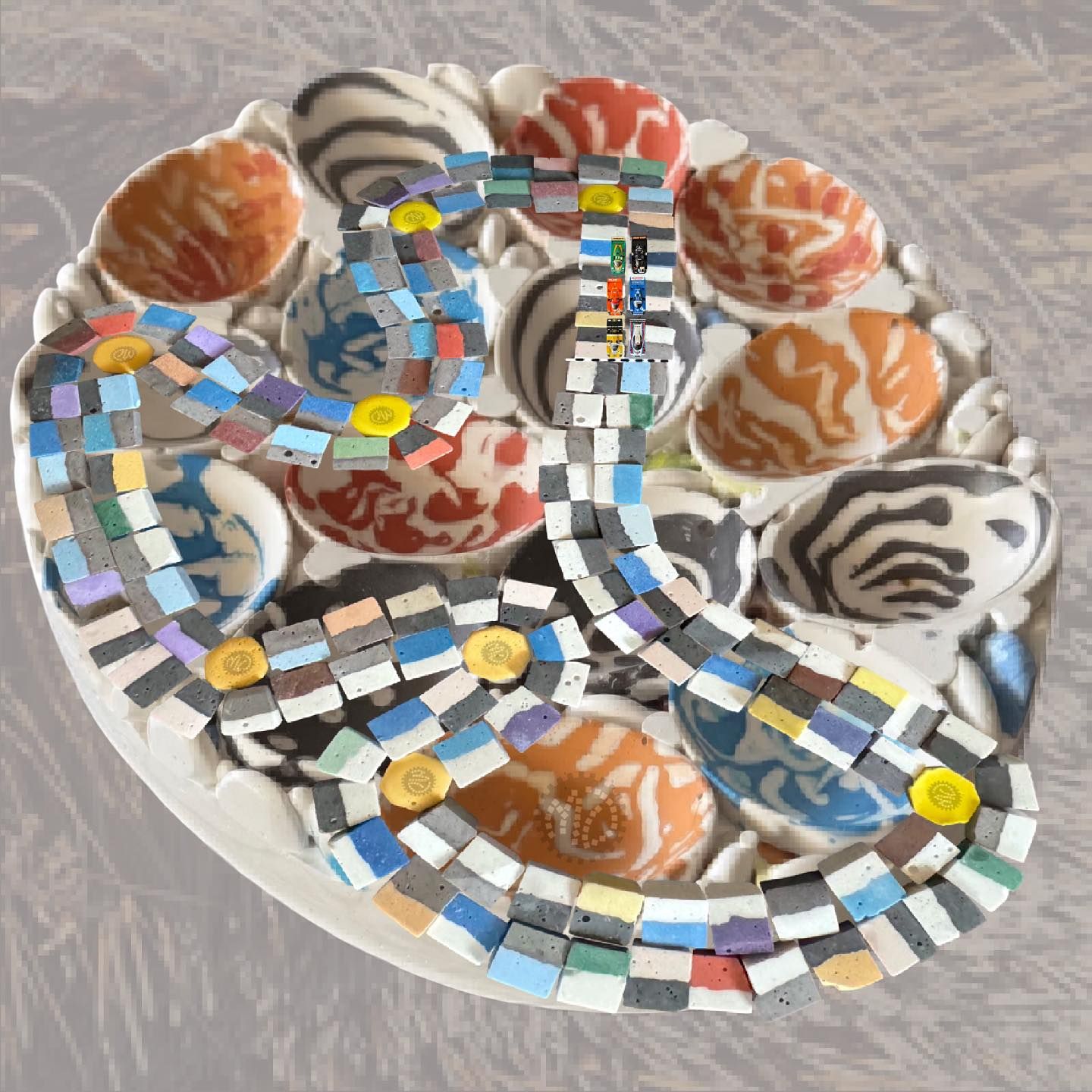 Colourful mosaic pattern winding through a tray of creatively painted eggs with abstract designs, set against a textured background.