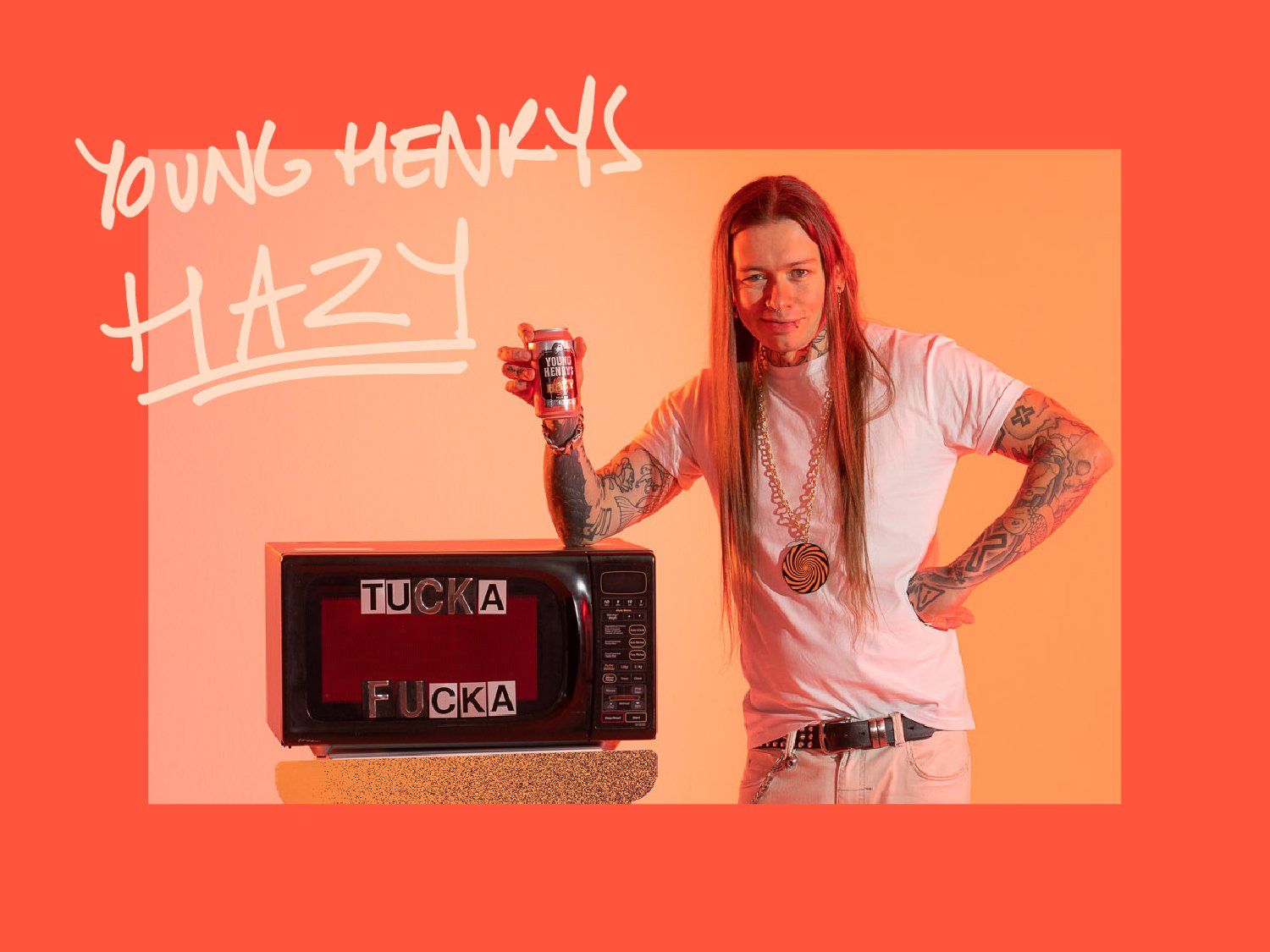 Person with long hair and tattoos holding a can, standing next to a microwave displaying "TUCKA FUCKA." Background is orange with text "YOUNG HENRY'S HAZY."