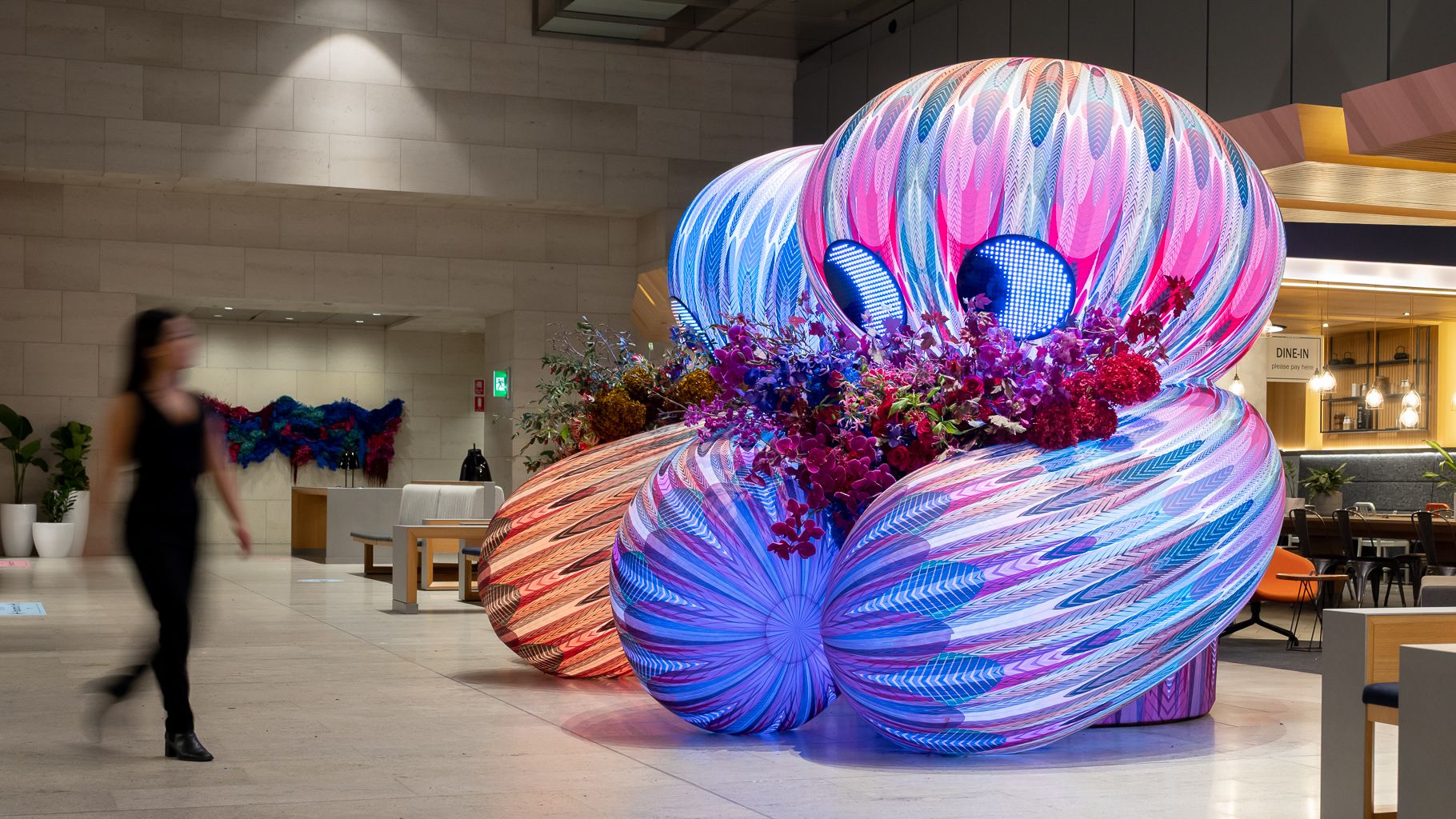 Two inflatable characters holding bunches of flowers in building foyer