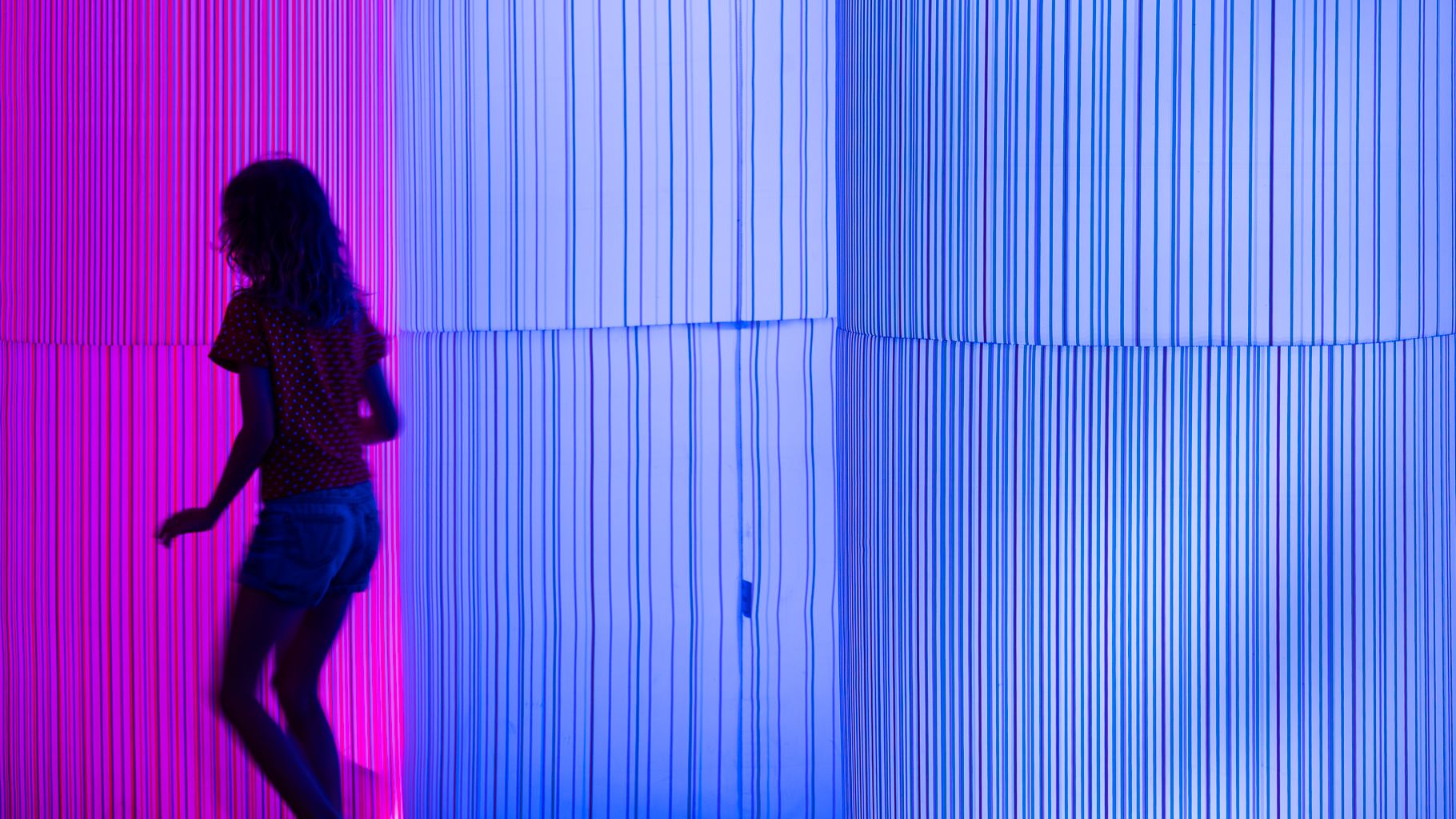 Silhouette of a young girl in front of light installation