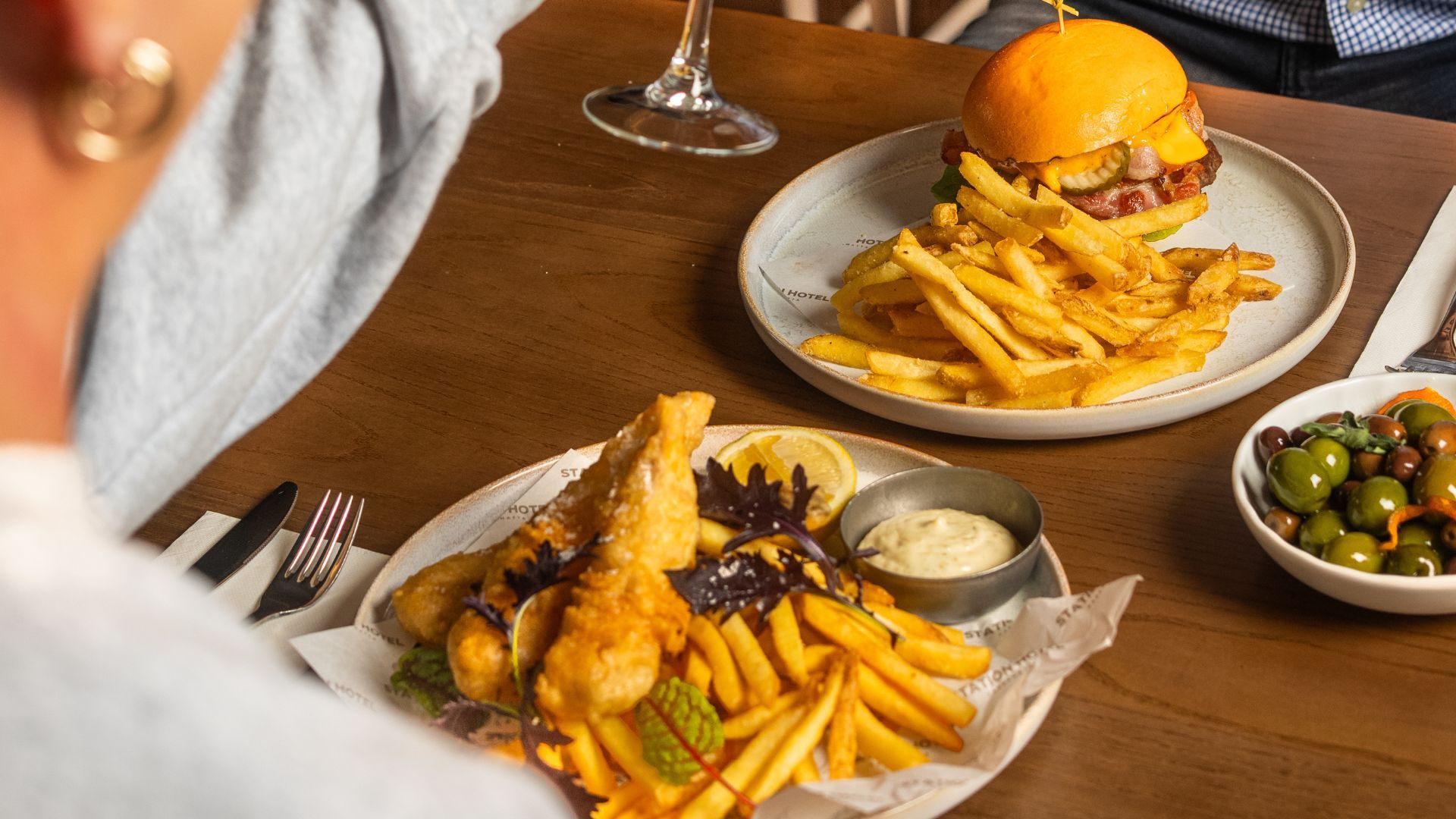 two plates of pub classic food on a table with people dining