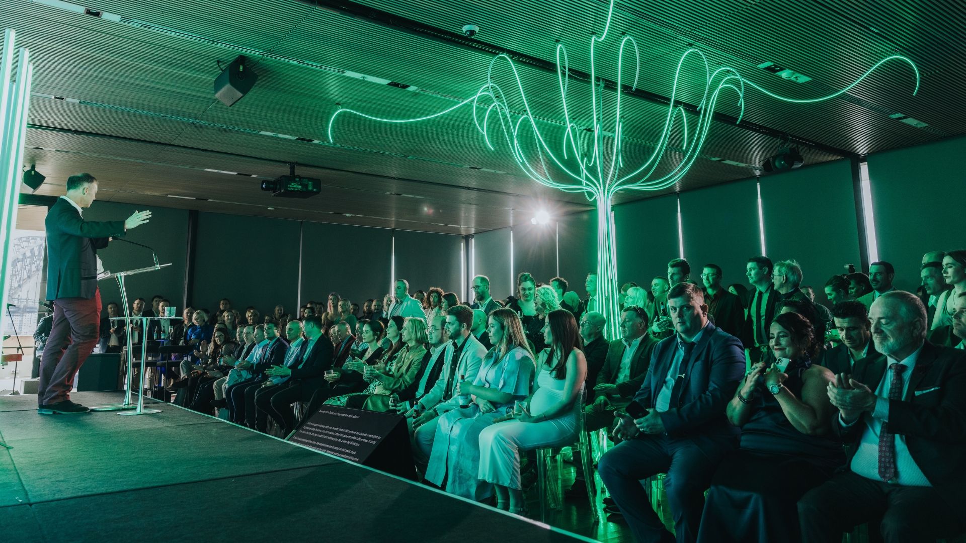 A speaker on stage and a neon tree installtion