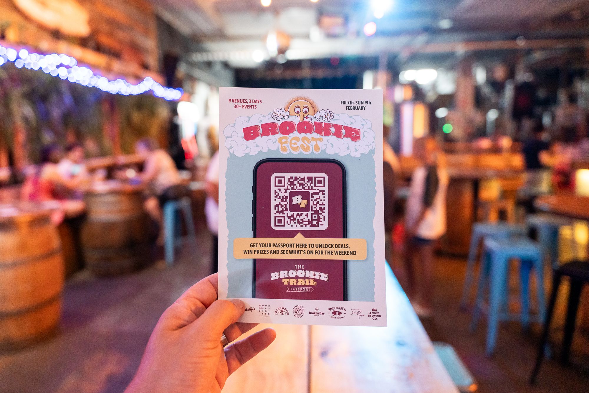 A hand holds a Brookiefest Hoppy Trails digital passport flyer