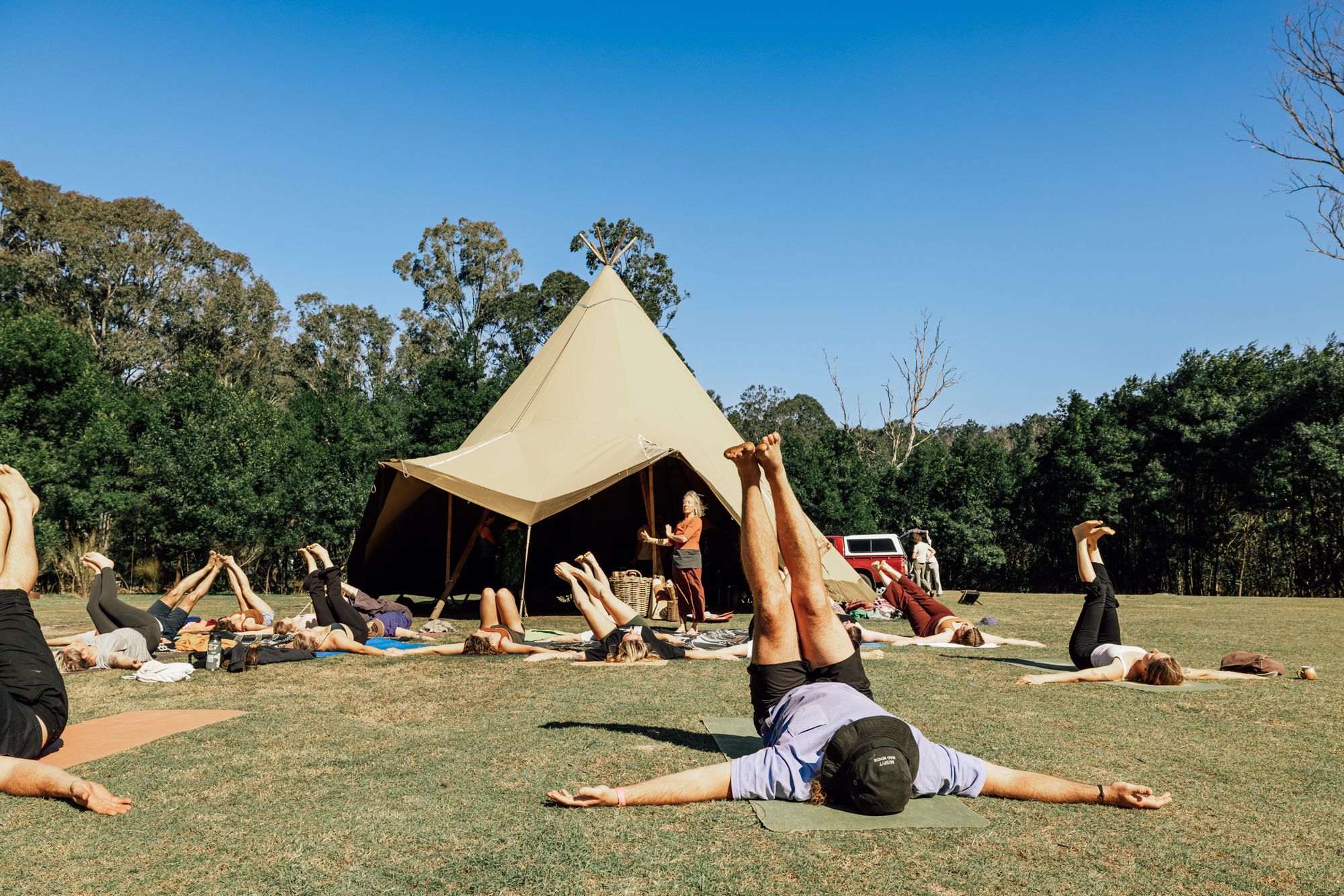 People stretching in front of a canvas tipi