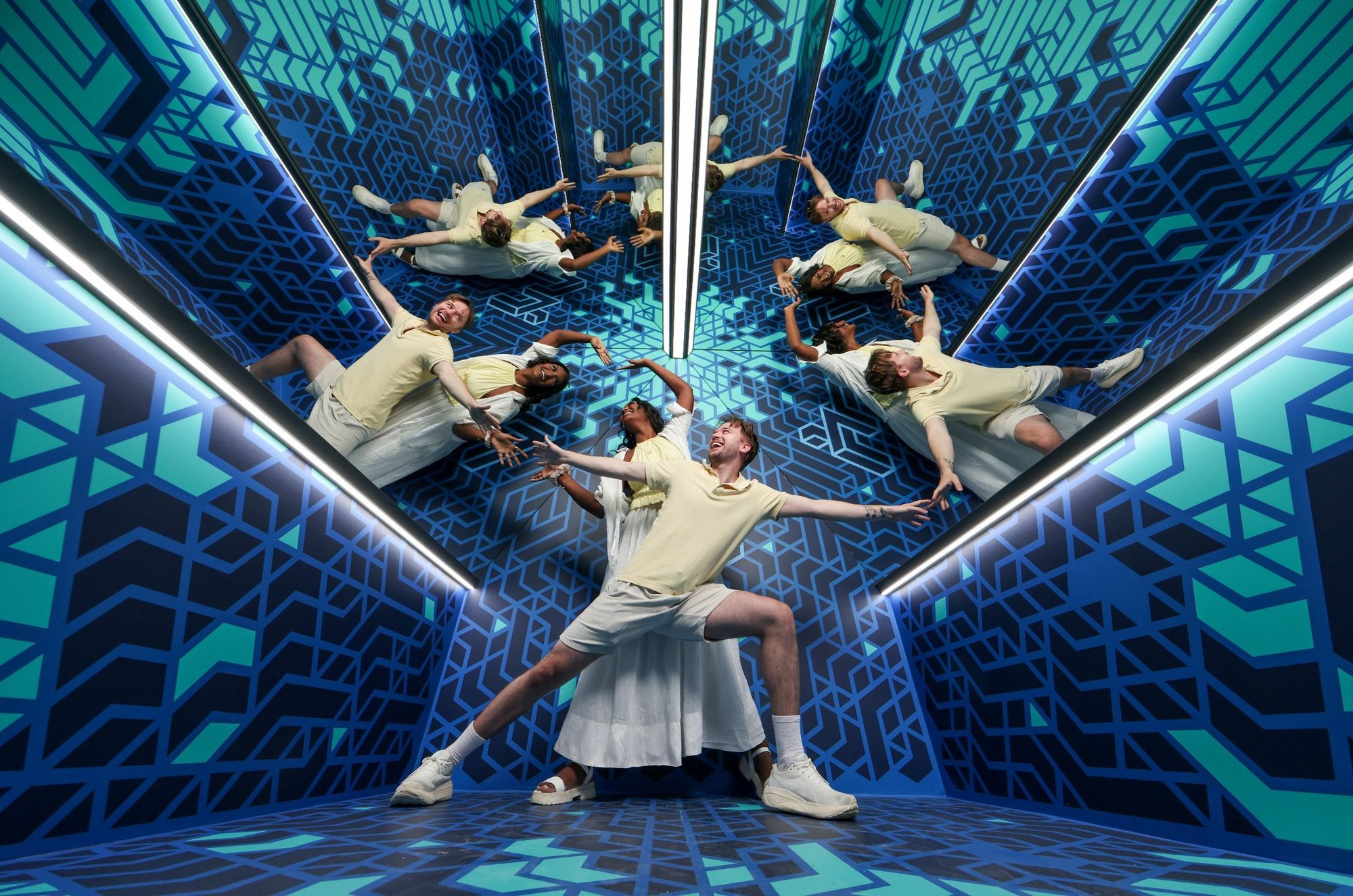 Two guests exploring the Clone room illusion where mirrors duplicate their image multiple times like a Kaleidoscope.