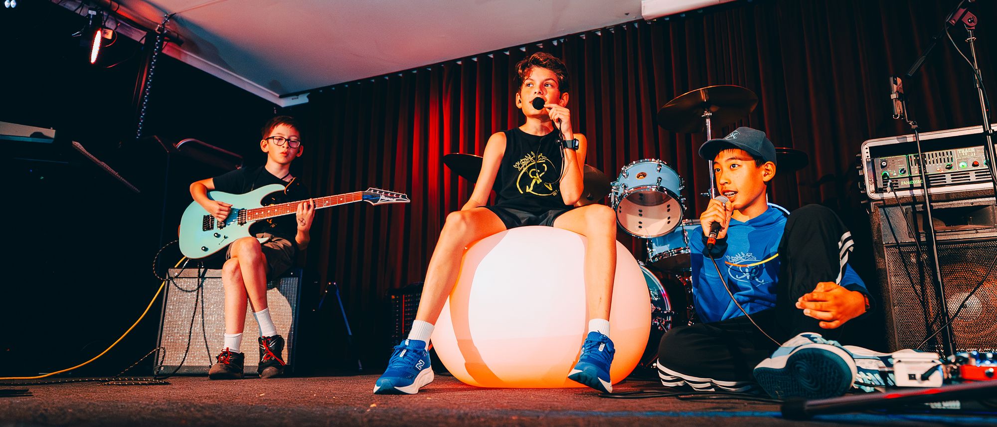 REVERSE REVOLUTION on stage with 11-year-old Owen on the electric guitar, and 12-year-old Deon and 13-year-old Axel singing into headset mics.