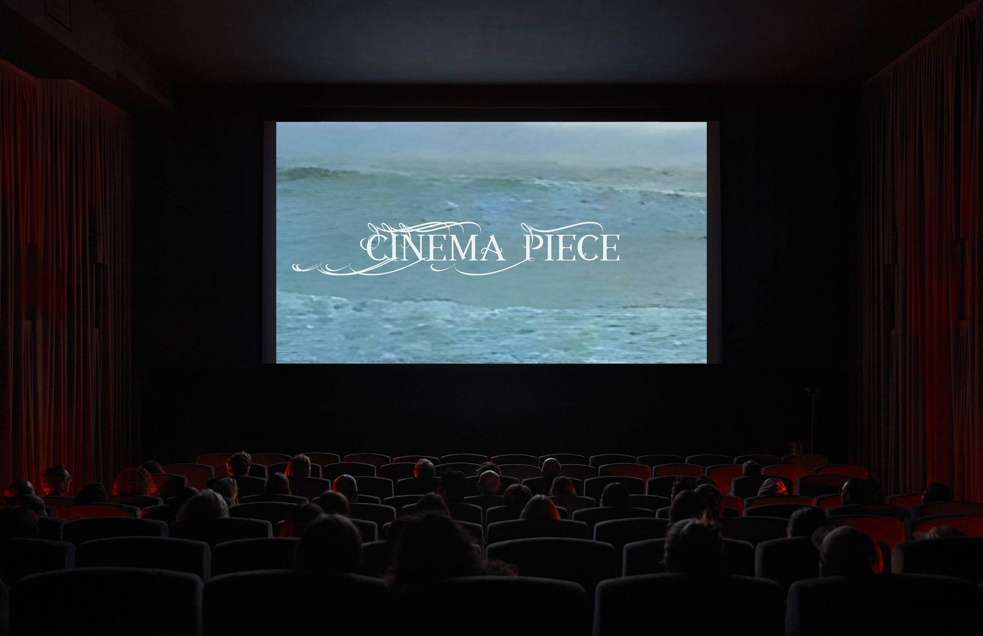 Audience seated in a dark cinema watching a screen showing ocean waves with the words 'Cinema Piece' in ornate white text.