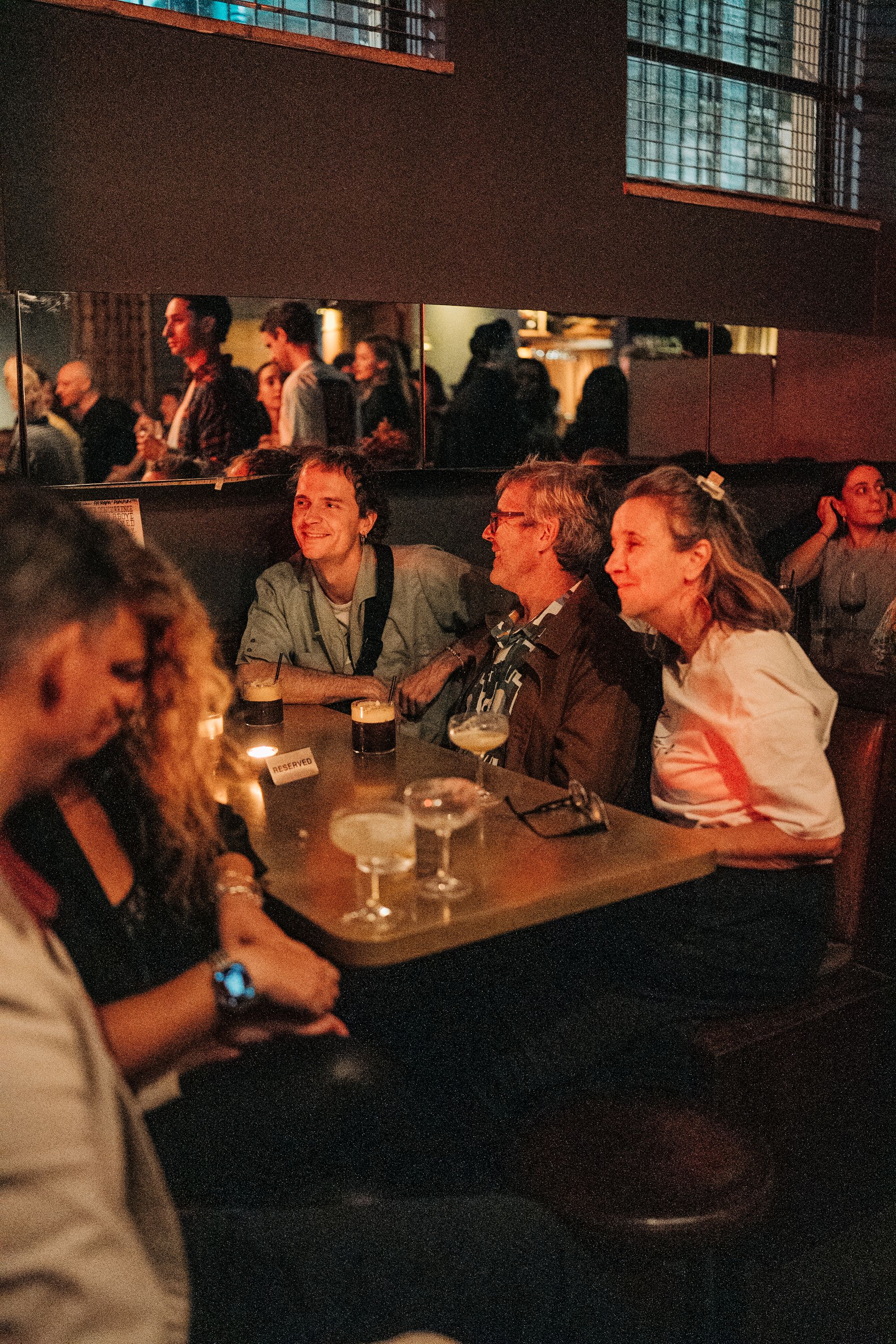 A table of three people sitting in a booth enjoying live music