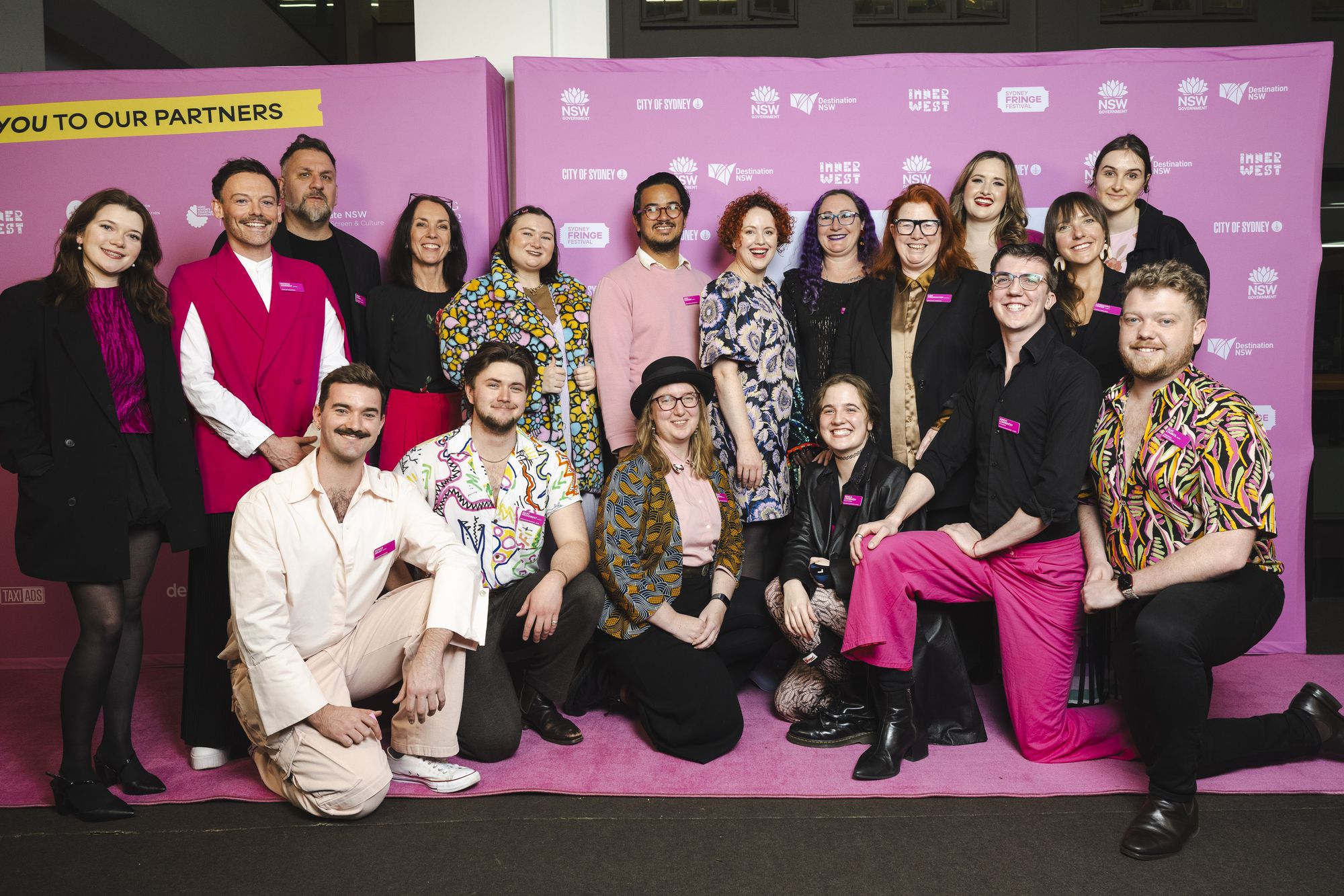 The Sydney Fringe Festival team dressed up in front of the Fringe media wall pose for a photo at the program launch