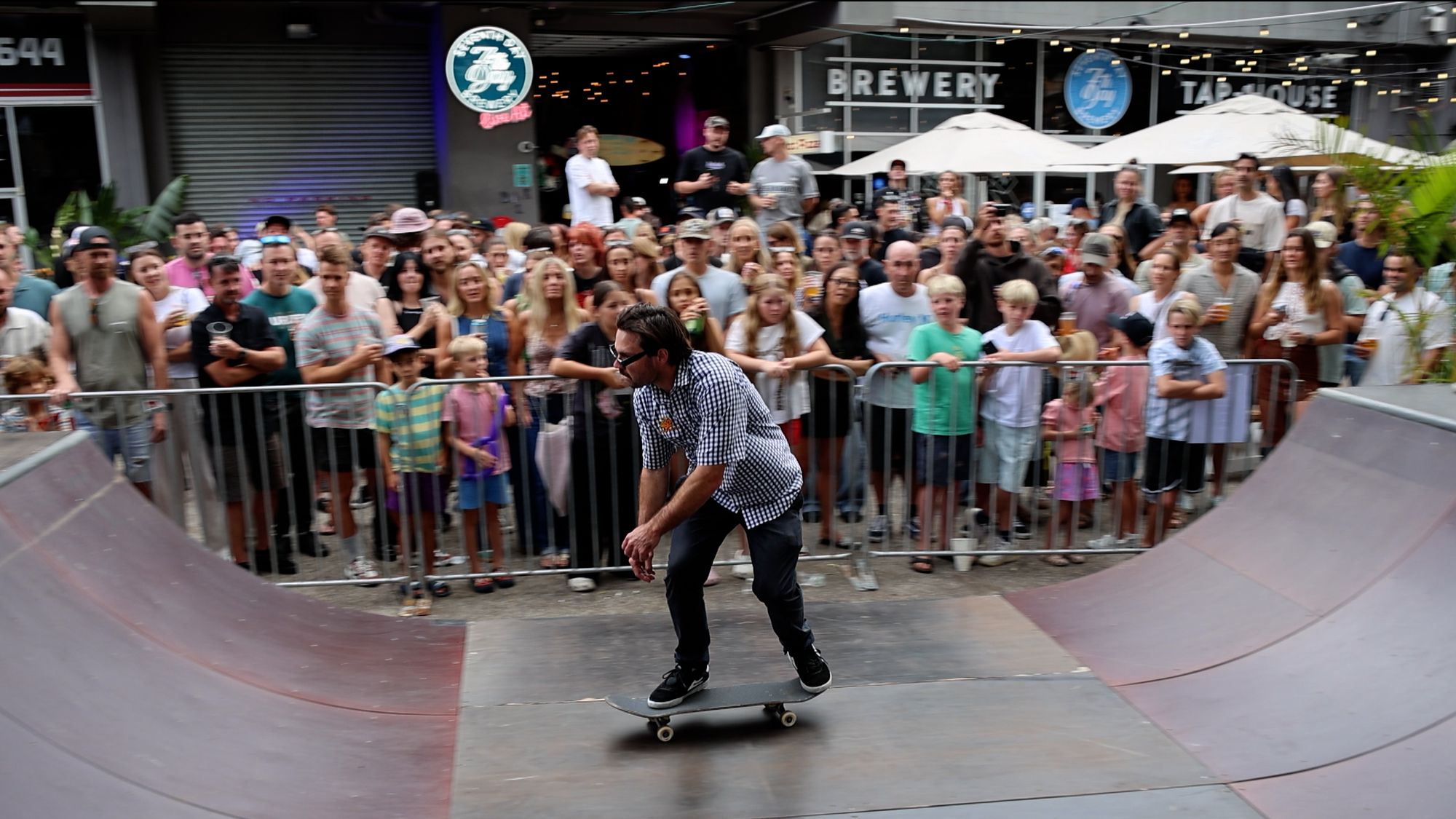 Skateboarder provding a demonstration on a half pipe in front of a crowd.