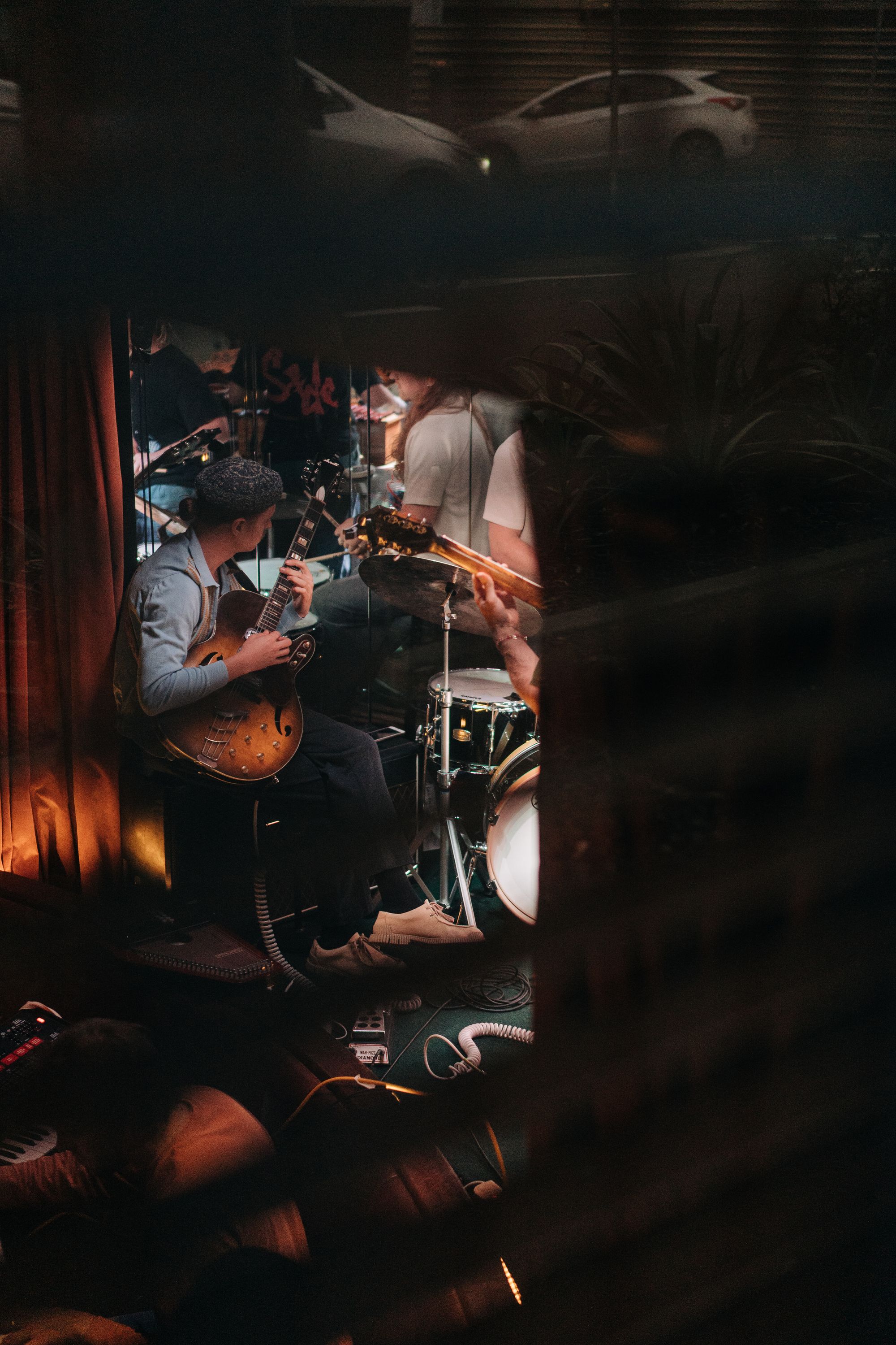 A man in the background of musical equipment playing electric guitar