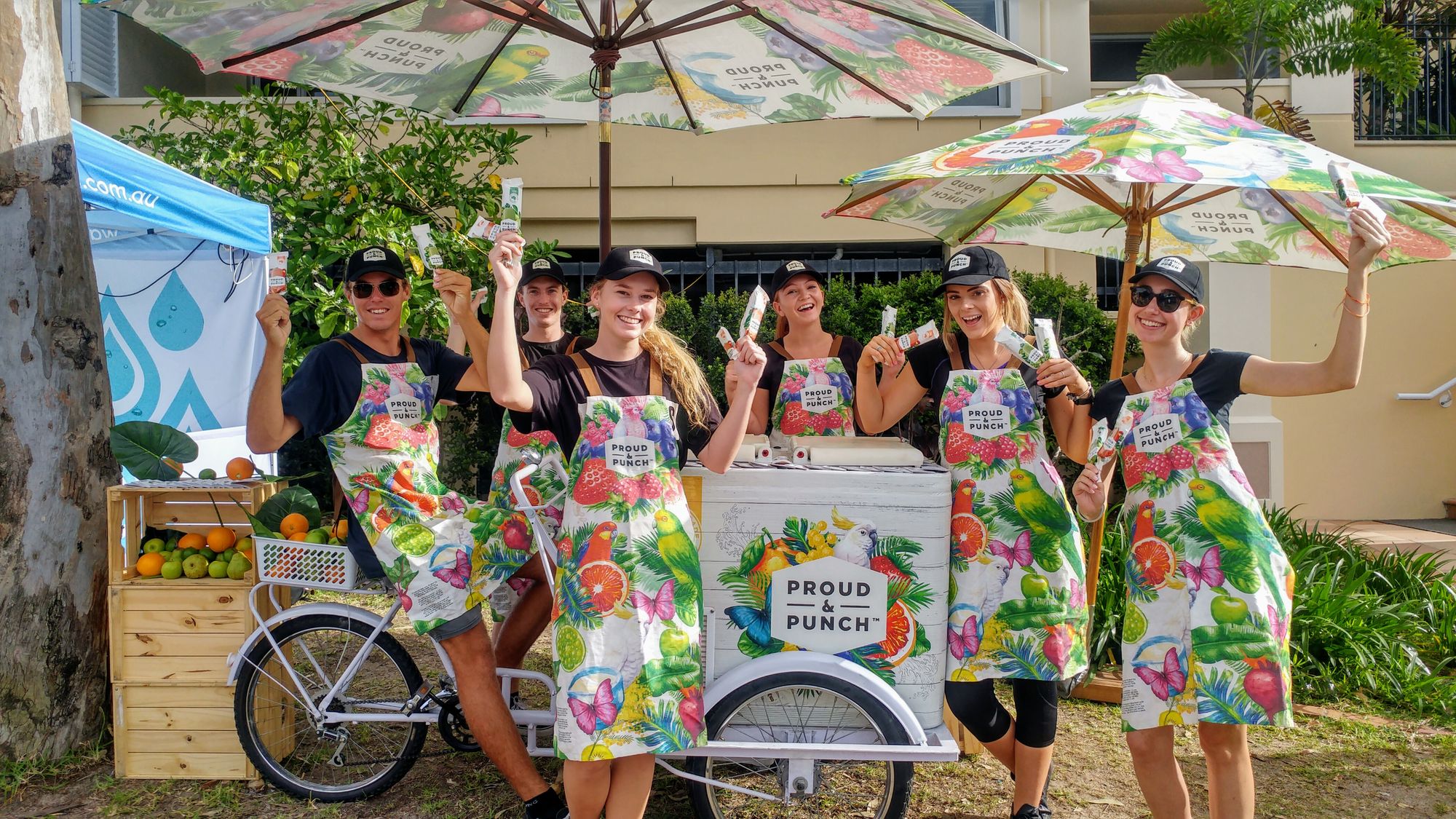 A group of people holding up ice creams in front of a branded bike