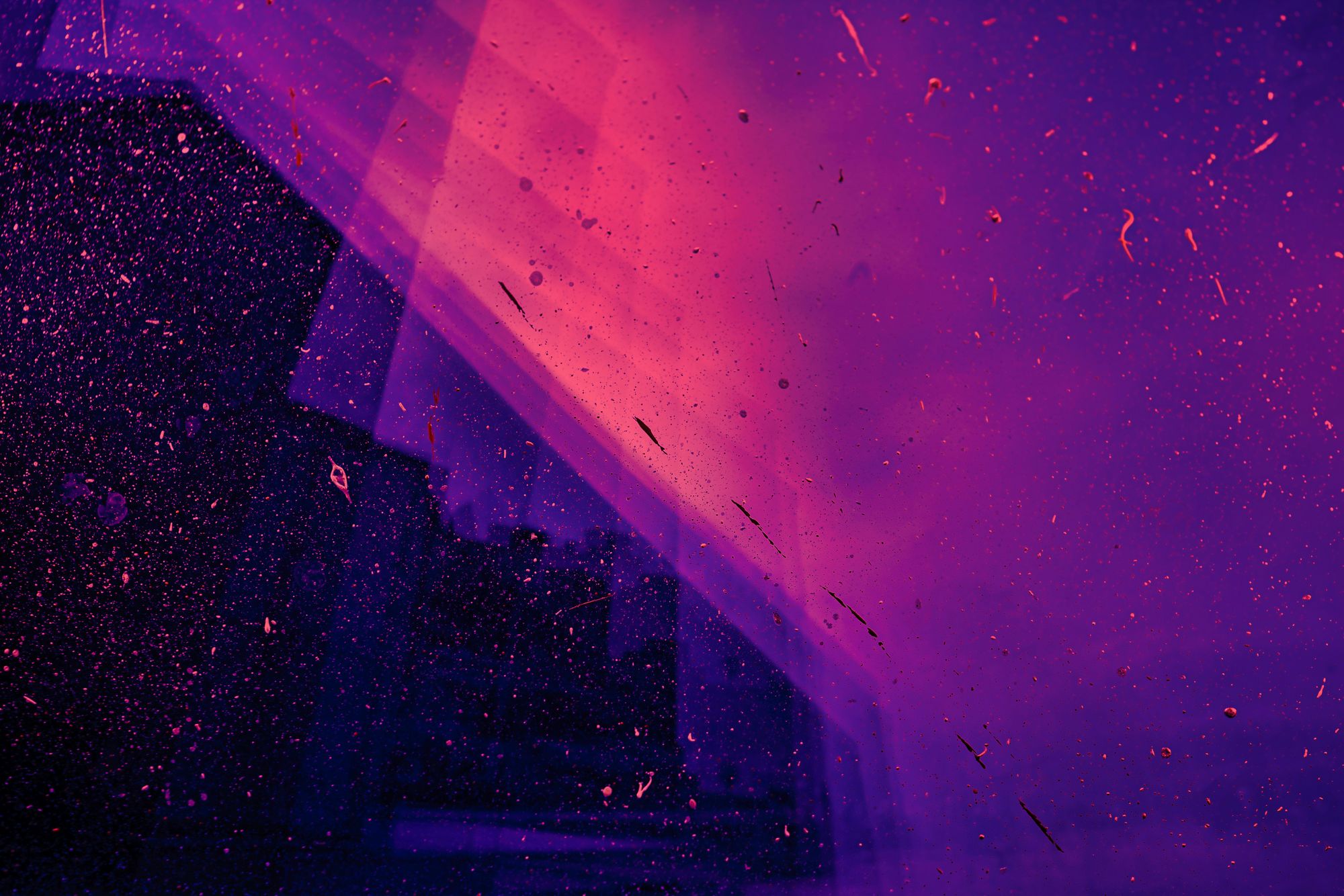 Abstract image with vibrant purple and pink hues, featuring scattered specks and scratches, creating a cosmic or dreamy atmosphere.