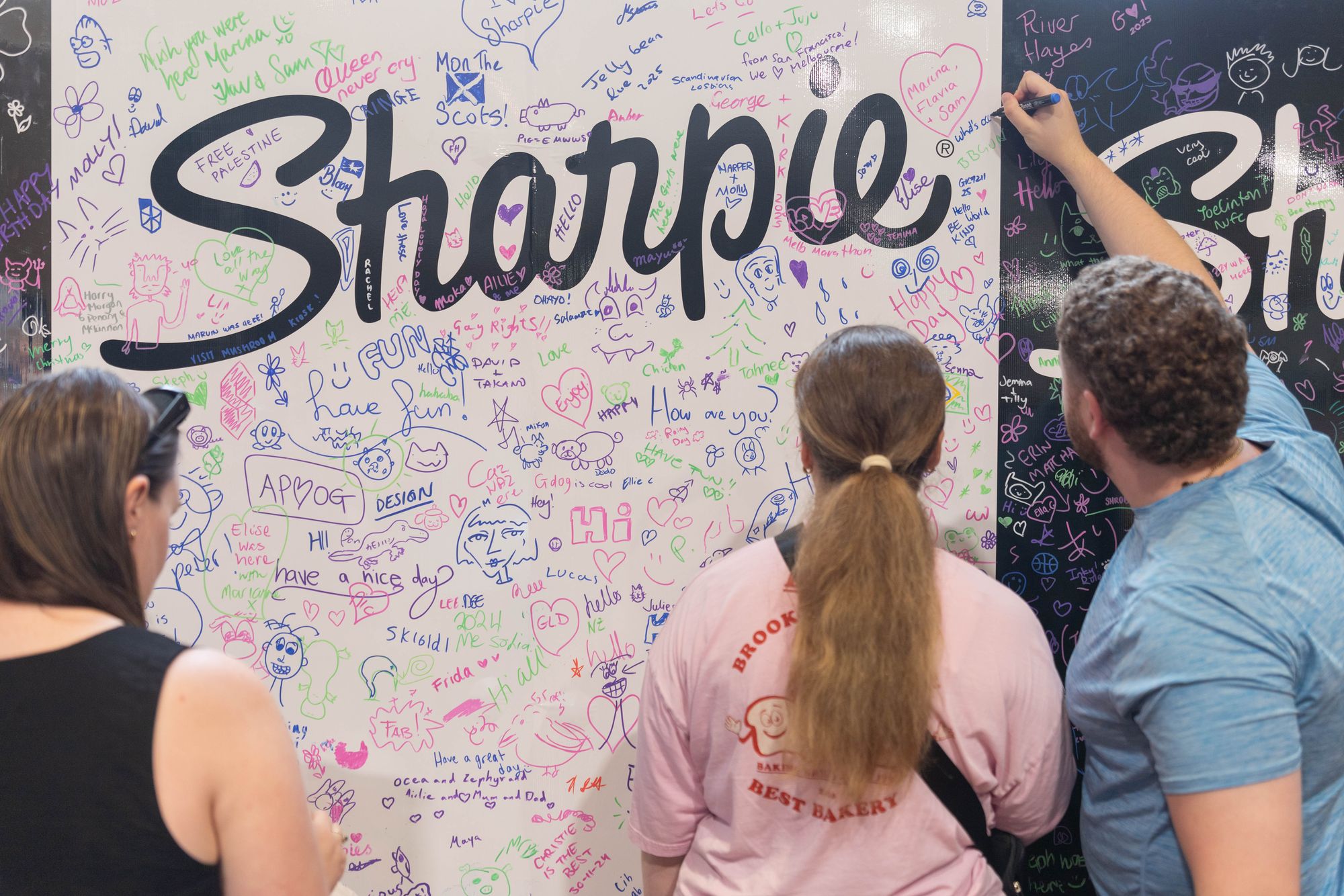 3 people drawing on a board with the Sharpie logo