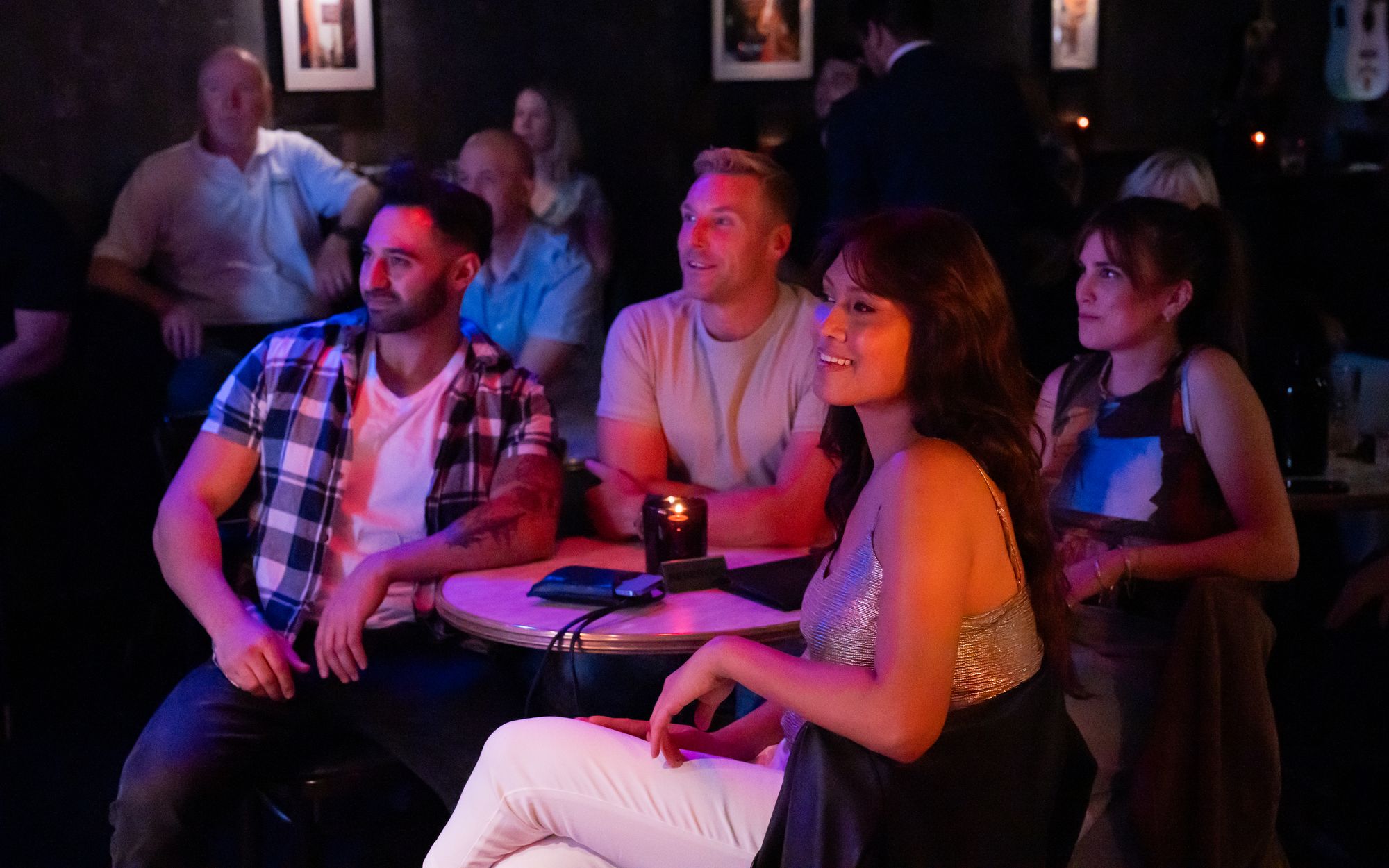 Four people smiling in the audience of a live show