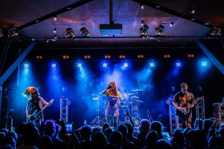 Four piece band rocking on stage in front of large audience
