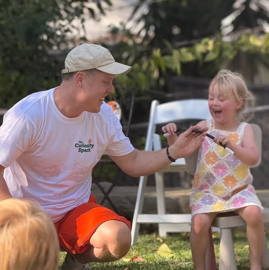 The Curiosity Spark entertainer performing a magic trick with a child at a birthday party