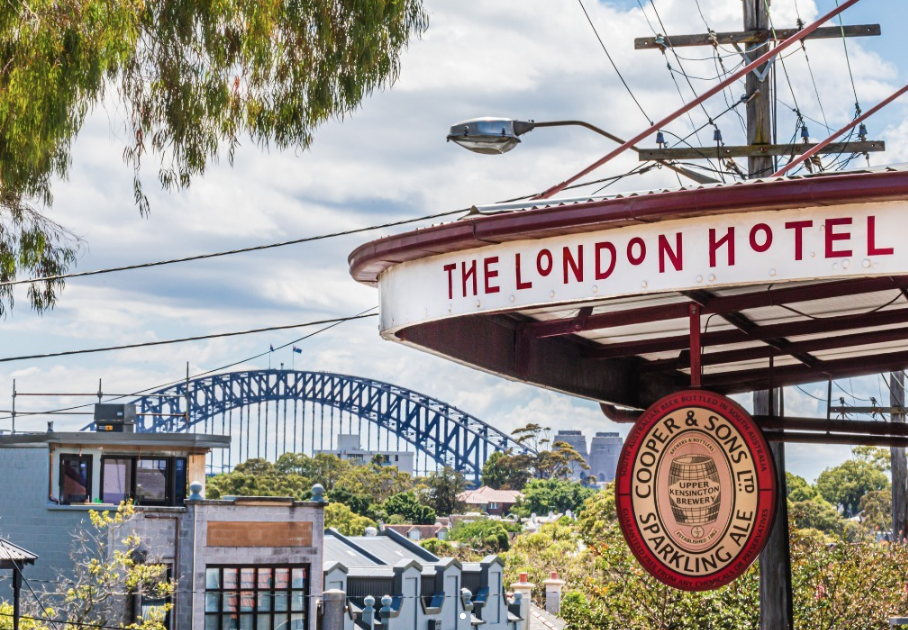 The exterior signage of The London Hotel in Balmain. There is a view of the Harbour Bridge in the background.