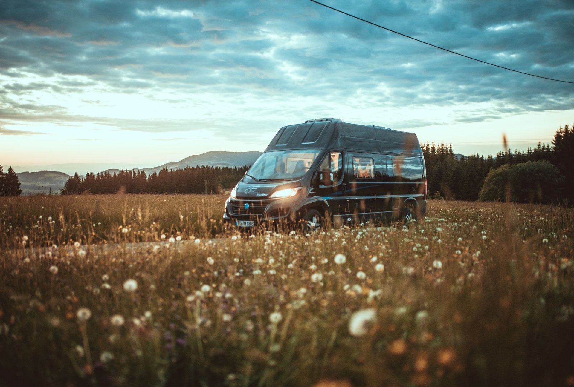Camper fährt bei Sonnenuntergang durch die Berge