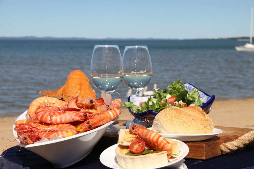 Aussie food festival: Outdoor picnic with market stalls under a bright blue sky.