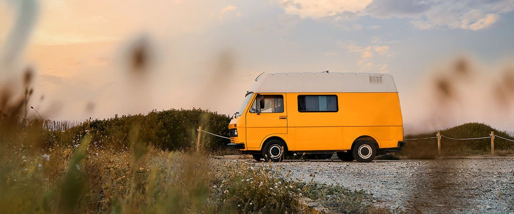 Furgoneta camperizada estacionada en la naturaleza con mesa y sillas de camping.