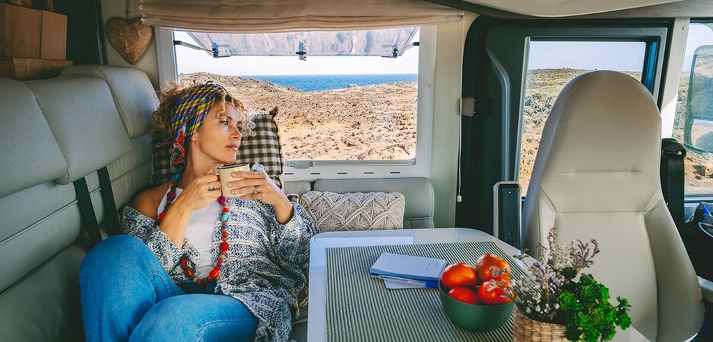 Autocaravana estacionada en camping con toldo abierto y sillas, ambiente vacacional.