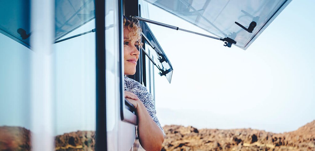 Autocaravana estacionada en un camping con toldo extendido y sillas fuera, ambiente vacacional.