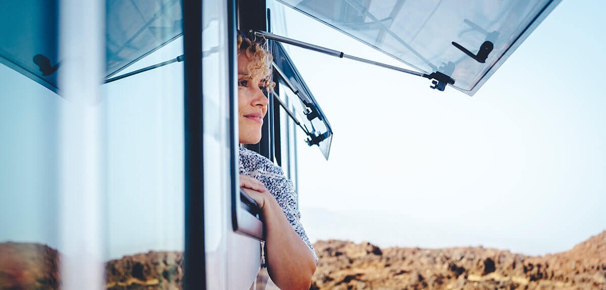 Autocaravana estacionada en un camping con toldo extendido y sillas fuera, ambiente vacacional.
