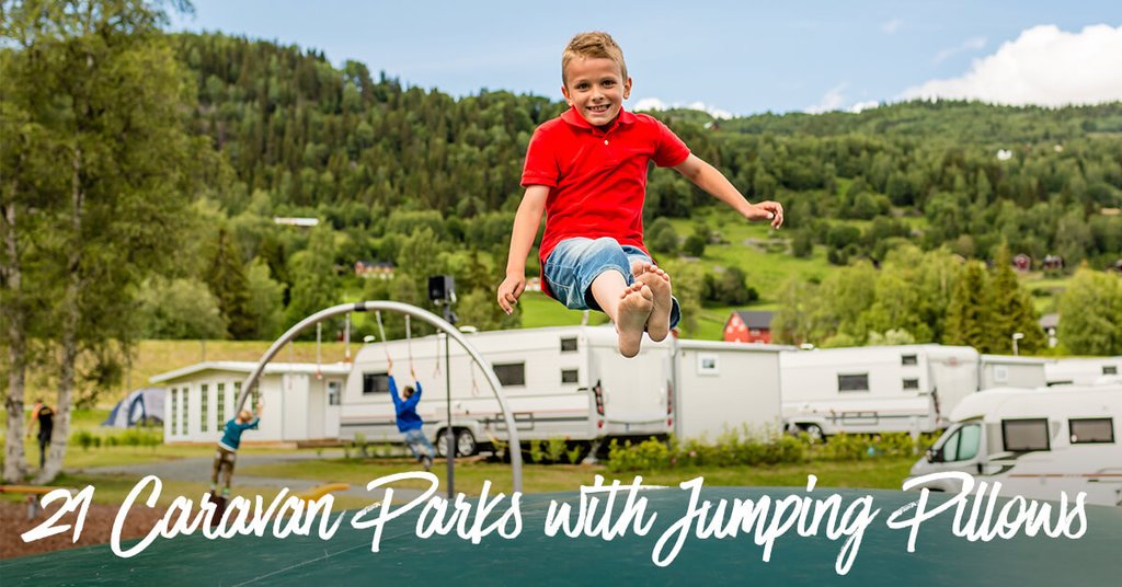 Kids on jumping pillow at caravan park, happy family camping holiday.