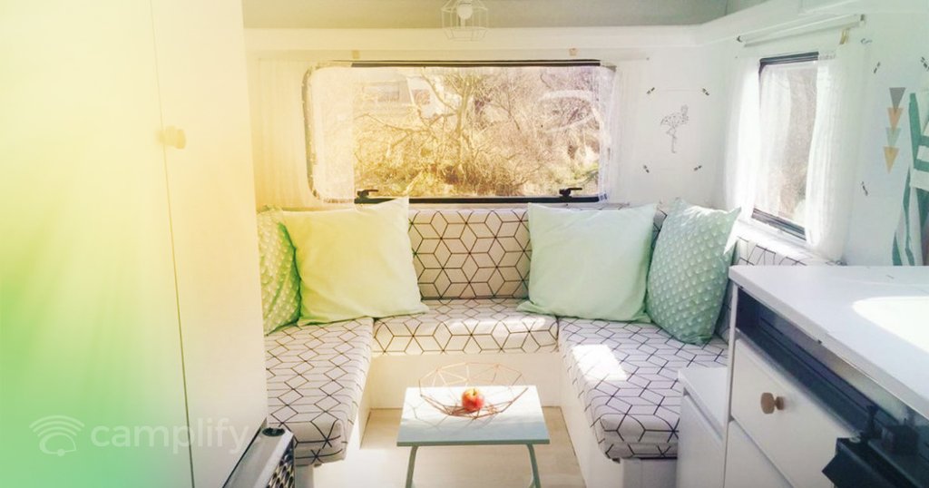 Caravana renovada aparcada en la naturaleza con mesa y sillas de camping.