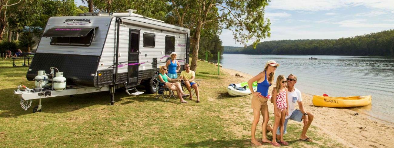 Autocaravana estacionada en la naturaleza; pareja sonriendo y disfrutando del camping.