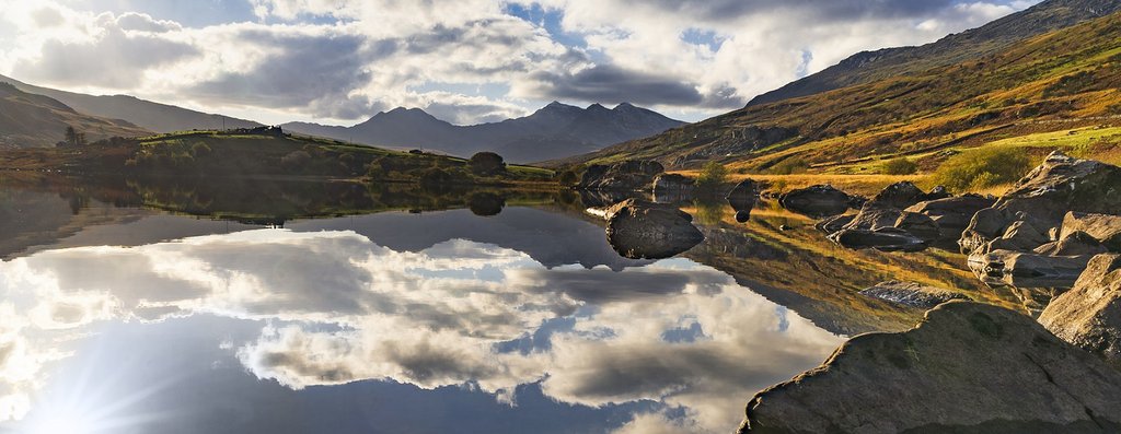 Family hiking along a scenic Welsh coastal path, enjoying summer sunshine and sea views.