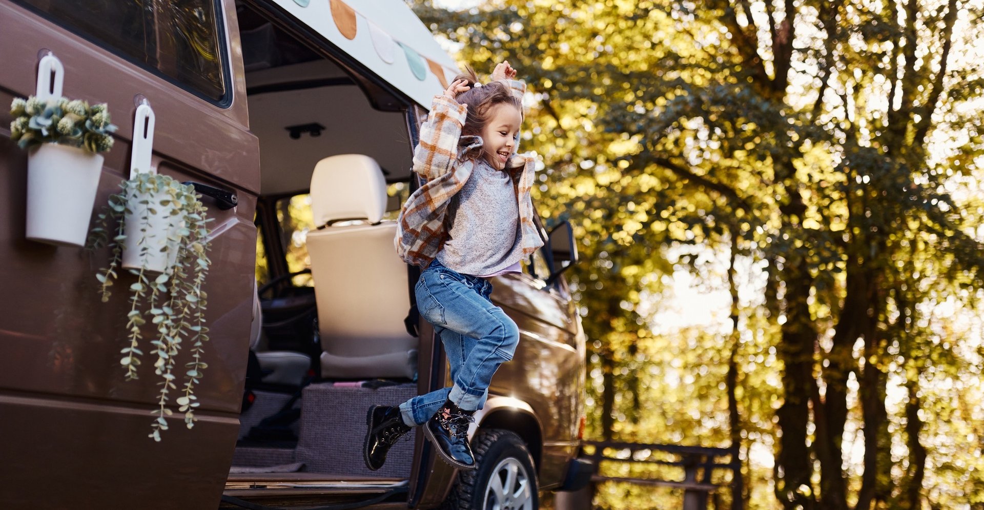 Herbstcamping mit Kindern: Familie am Lagerfeuer, Wohnwagen auf dem Campingplatz.