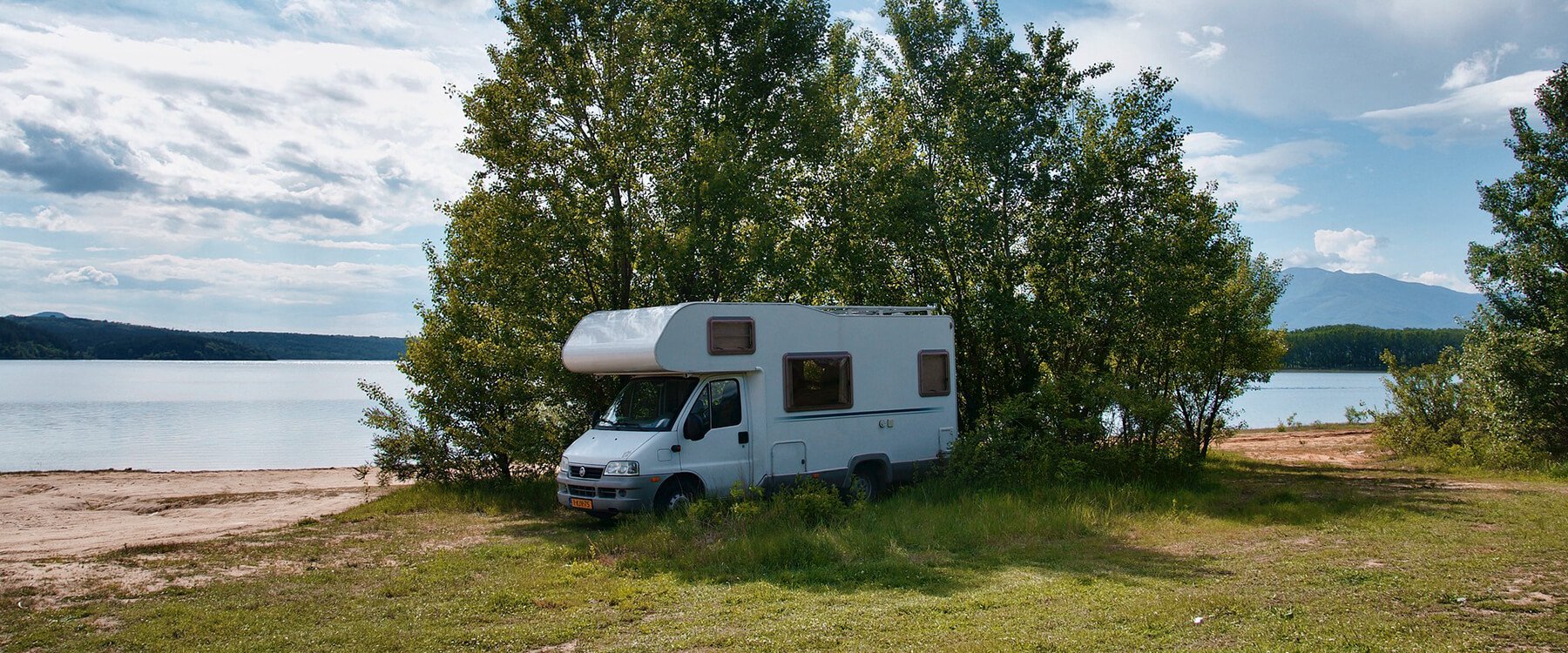 Autocaravana circulando por carretera costera en España con el mar de fondo.