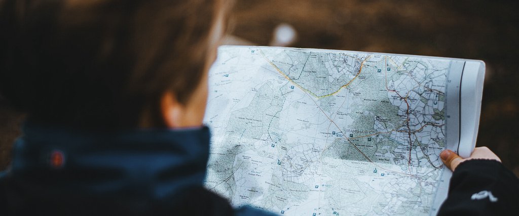 Road trip: Car packed with camping gear parked on a scenic overlook, map spread on bonnet.