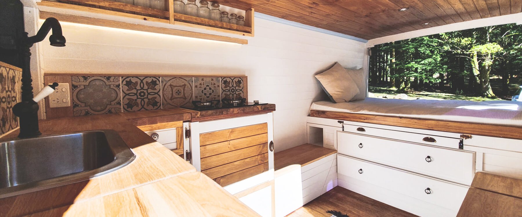 Furgoneta camper amarilla en la naturaleza, con mesa y sillas de camping al lado.