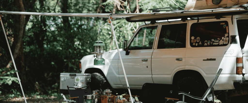 Caravan awning pitched at sunny campsite, holidaymakers relaxing outside.