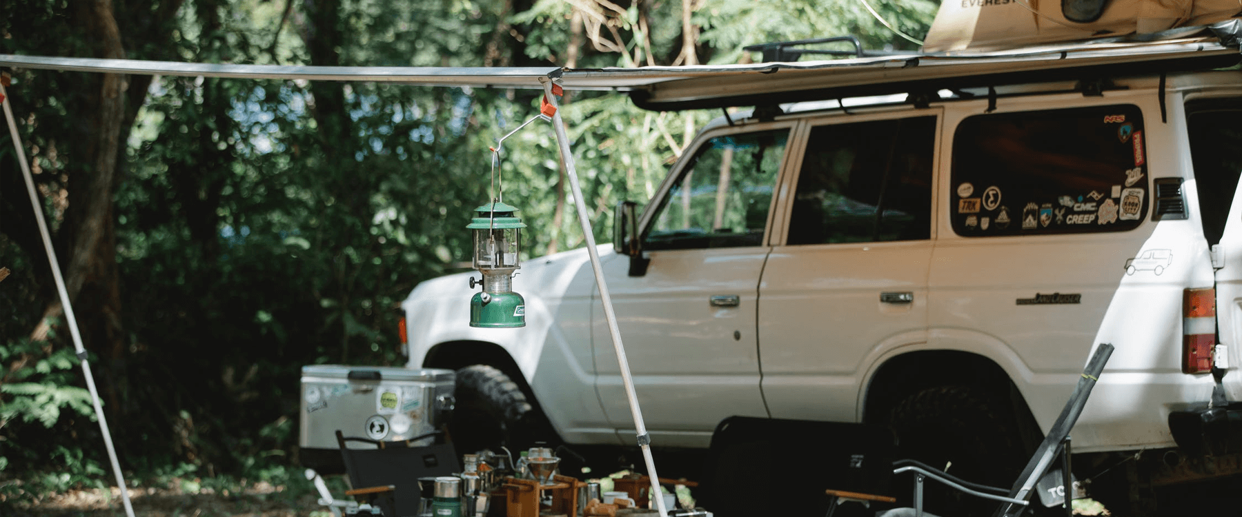 Caravan awning pitched at sunny campsite, holidaymakers relaxing outside.