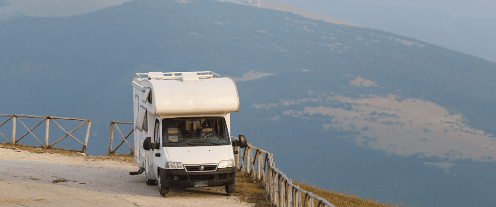 Campervan parked by a loch, ready for a staycation. Enjoy the freedom of motorhome holidays and rentals.