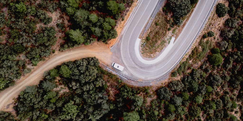 Autocaravana viajando por carretera en paisaje de montaña. Vacaciones y aventura en camper.